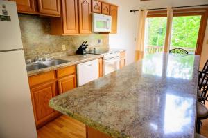 a kitchen with wooden cabinets and a granite counter top at Moonbeam Chalet in Logan +9 photos