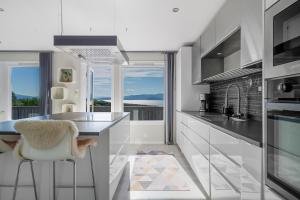 a kitchen with white cabinets and a counter with a stool at Panorama view! Modern,Balcony/parking in Bodø +12 photos