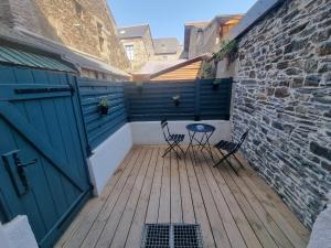 a patio with two chairs and a table on a wooden deck at Studio pour 2 en plein centre-ville in Dol-de-Bretagne