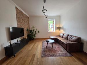 a living room with a brown leather couch and a flat screen tv at Single Malt Apartment in the old distillery in Inverlochy