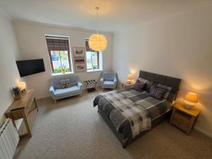 a bedroom with a bed and a couch and a chair at Single Malt Apartment in the old distillery in Inverlochy