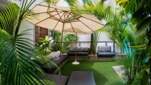 a courtyard with chairs and an umbrella and plants at Mango Tree Ipanema in Rio de Janeiro