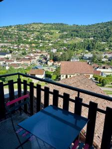 a balcony with a table and a view of a city at Hôtel Restaurant & Bien-être Le Chalet des Roches in La Bresse