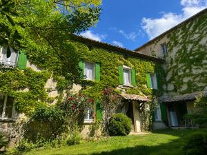 a building covered in ivy with flowers on it at Le Degoutaud in Le Barroux
