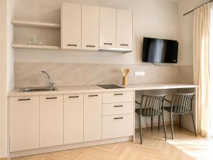 a kitchen with white cabinets and a table and chairs at Maria's Studios in Frangokastello +25 photos