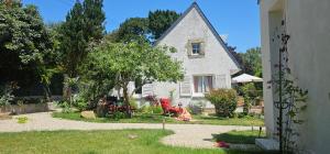 a white house with a yard with chairs in front of it at Chambre d'hôtes Le Havre in Saint-Coulomb