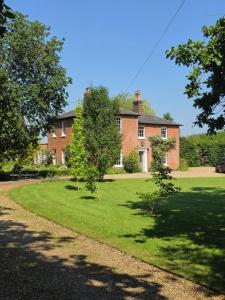 a large brick house with trees in front of it at Serenity Villa in Beccles