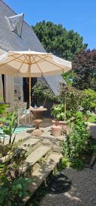 a patio with a table and an umbrella at Chambre d'hôtes Le Havre in Saint-Coulomb