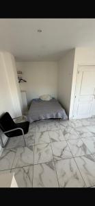 a bedroom with a bed and a chair on a tiled floor at Studio dans une villa in Perpignan