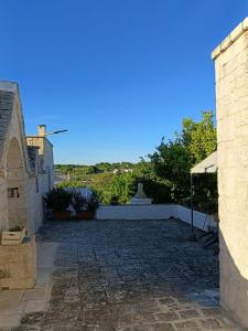 a stone walkway leading to a building with a statue at Trullo Le Tre Sorelle in Cisternino