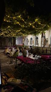 a group of people sitting at tables under lights at Gulzar Village Guesthouse in Dushanbe +13 photos