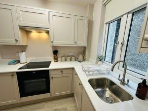 a kitchen with white cabinets and a sink at Stay 55 in Peebles