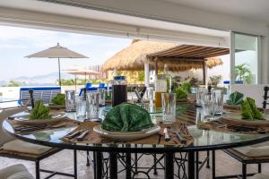 a glass table with plates and napkins on it at Villa MAJUM Acapulco in Acapulco