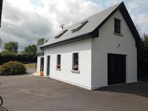 a white garage with a black roof at Five Valleys, Ballinastraw in Bunclody