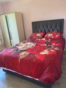 a bed with a red comforter with roses on it at Sunrise House in Cahersiveen