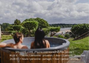 two people sitting in a hot tub looking at a river at Château de Candes - Art & Spa in Candes-Saint-Martin