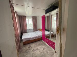 a small bedroom with a bed and a pink wall at Kutbi Guest House in Bokonbayevo