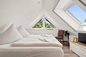 a white bed in a room with two windows at Amelie in Greetsiel