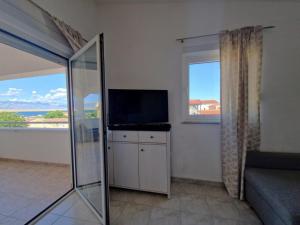 a living room with a flat screen tv and a window at Apartments Rosa Soldatica in Vir