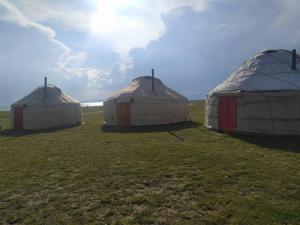 three domes in a field with the sun in the sky at Yurt camp Marat Son-Kul in Song-Kul