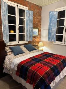 a bedroom with a large bed in a room with windows at Piccola Cucina: Casa centenária Vale dos Vinhedos in Garibaldi