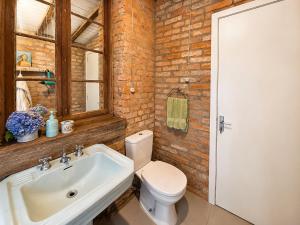 a bathroom with a white toilet and a sink at Piccola Cucina: Casa centenária Vale dos Vinhedos in Garibaldi
