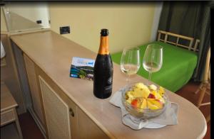 a bottle of champagne and a bowl of fruit and wine glasses at Hotel Viticcio in Portoferraio