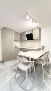 a white kitchen with a table and chairs at Apartments Zanic on The Beach in Podstrana +50 photos