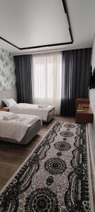 a hotel room with two beds and a rug at AMARANT hotel in Baysun