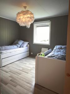 a bedroom with two beds and a chandelier at Flott hus på Tasta in Stavanger
