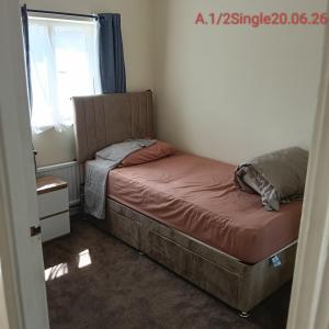 ein kleines Bett in einem Zimmer mit Fenster in der Unterkunft Double bedroom with shared facilities in Lexden