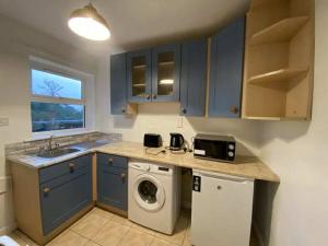 a kitchen with blue cabinets and a washing machine at Sunrise House in Cahersiveen