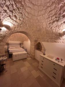 a bedroom with three beds and a stone wall at Trullo Le Tre Sorelle in Cisternino