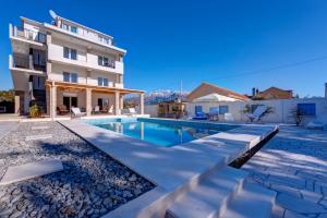 a villa with a swimming pool in front of a building at Villa Sandy Apartments in Tivat