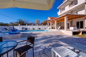 a patio with a table and chairs and a swimming pool at Villa Sandy Apartments in Tivat