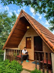 a man sitting on the porch of a small house at caminho das montanhas chalé in Itanhandu