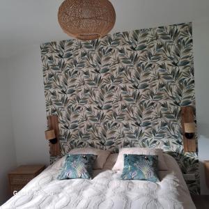 a bed with two pillows in front of a wall at LE 37 croix in Gennes