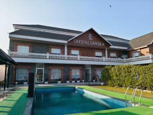 a building with a swimming pool in front of it at Crystal Garden in Lalru
