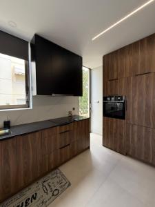 a kitchen with black and wooden cabinets and a window at Notos Suites in Athens