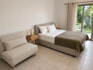 a bedroom with a bed and a chair and a window at Maria's Studios in Frangokastello