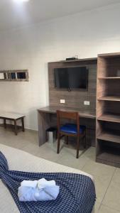 a room with a desk with a tv and a chair at Hotel Casarão Pitangueiras in Guarujá