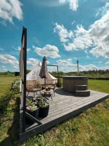 a wooden deck with a chair and an umbrella at Glempings MIGLA in Dalbe +23 photos