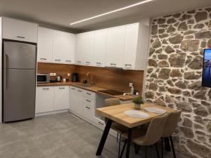 a kitchen with a wooden table and a stone wall at Amara Centro Luxury Apartments in Mouzaki
