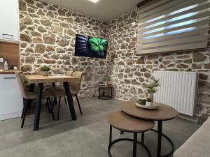 a living room with two tables and a tv on a stone wall at Amara Centro Luxury Apartments in Mouzaki +2 photos