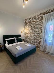 a bedroom with a large bed and a stone wall at Amara Centro Luxury Apartments in Mouzaki