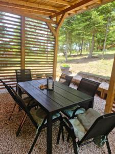 ein schwarzer Tisch und Stühle unter einer Holzpergola in der Unterkunft Pineta in Nišići