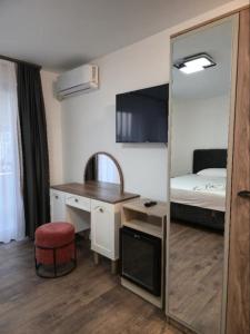 a room with a desk and a bed with a mirror at Hotel Boheme in Peje