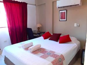 ein Schlafzimmer mit einem großen weißen Bett und roten Kissen in der Unterkunft Hotel Arthaus in Asunción