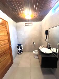 a bathroom with a toilet and a sink and a light at Black Pearl in Puerto Villamil