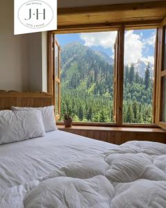 two beds in a bedroom with a large window at Jaaz Heights in Tāl